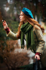 Close up portrait of a redhead  Beautiful girl in a green scarf and blue hat standing on colorful...