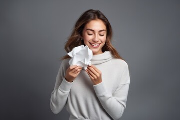 happy smiling woman or girl with paper napkins, who has recovered from a cold, flu or covid on grey background