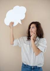 beautiful woman holding white speech bubble in front of brown background