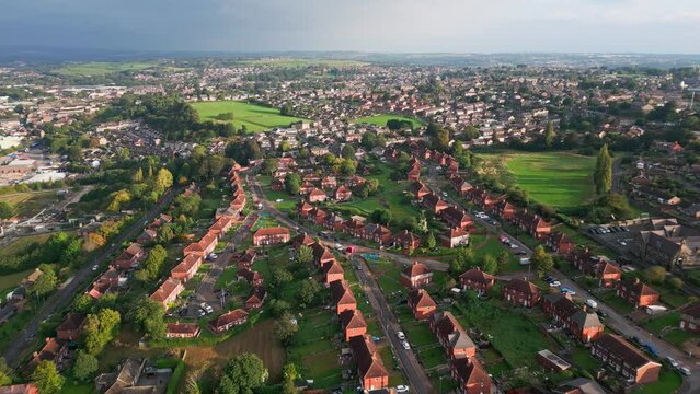 Yorkshire's housing scene: Red brick council estate, aerial drone shot, sunny morning, people strolling about.