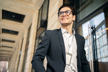 Obraz premium A successful manager with dark hair and glasses. A young male entrepreneur in a business suit clothes. A confident person smiles at an office employee.