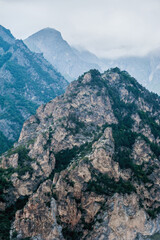 Mountain peaks with trees against a background of cloudy sky and clouds