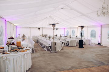 shot of the wedding hall decorated with flowers and lights, tables set with cutlery and beautiful...