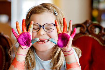 Little preschool girl painting with felt pens on hands. Creative cute child showing hands and arms...