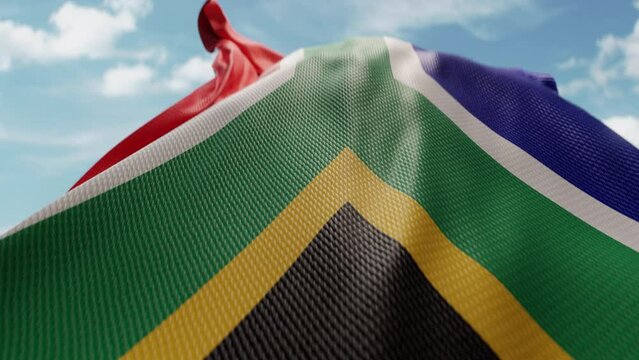 Wavy flag of South Africa blowing in the wind in slow motion. Waving official South African flag team symbol abstract vertical background. Blue sky with clouds. World countries flying flags concept