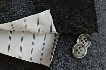 Two unfastened buttons of a grey suit jacket. Nowadays, most sleeve buttons cannot be unfastened...