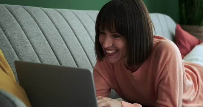 A joyful Caucasian woman can be seen in front of laptop, radiating happiness as she celebrates receiving good news. Her elated expression reflects a moment of triumph and positivity in digital world.