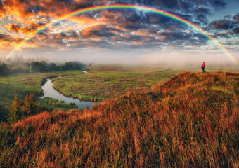 rainbow over the meadow. tourist enjoys the view. scenic landscape