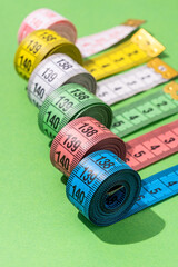 colorful measuring tapes top view on bright green background