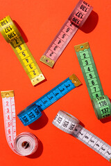 colorful measuring tapes top view on bright red background