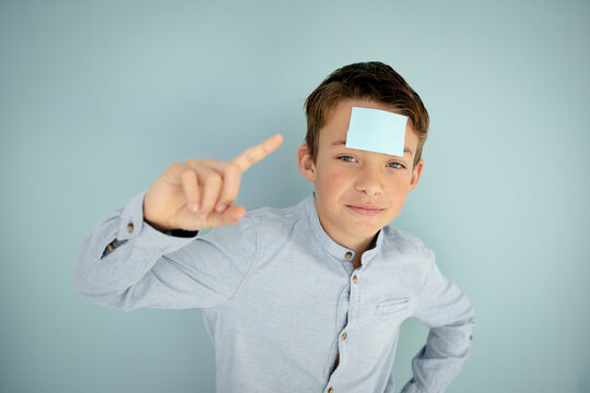 cool young boy with blue sticky note on his forehead in front of blue background