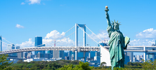 Tokyo, Japan. Odaiba, a popular tourist destination. A replica of the Statue of Liberty and the cityscape of Tokyo. - obrazy, fototapety, plakaty