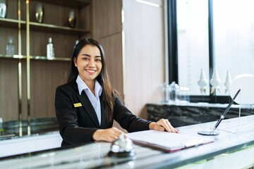 Beautiful asian hotel receptionist in  uniforms at desk in lobby Friendly and welcome staff in hotel reception counter. - obrazy, fototapety, plakaty