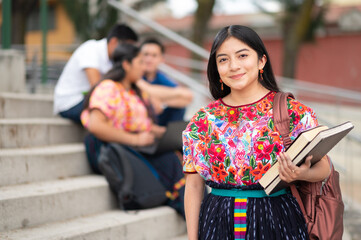 Latina student with books in her hand, enjoys the day at break time before the conference starts.