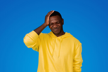 Sad young black guy presses hand to head, suffers from mistake and headache