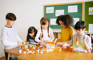Ethnicity diversity group of Elementary school playing with colorful blocks on table in classroom....