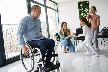 
A father, facing physical challenges, engages in lively play with his family in the living room,...