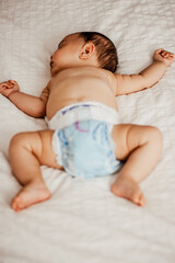 Adorable baby sleeping in swaddling clothes in a bed with hands upwards
