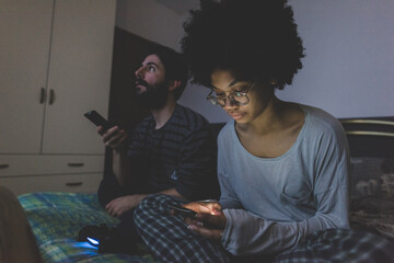 Young multiethnic couple bed using smartphone