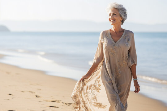 A Senior Old Beautiful Caucasian Woman Is Walking On The Sand With A Dress On An European Beach With A Calm Ocean - Summer Weather Beach Walk Relaxing