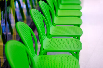 Modern green plastic chairs in a row. Design element and customer waiting in a line for business service concept background.