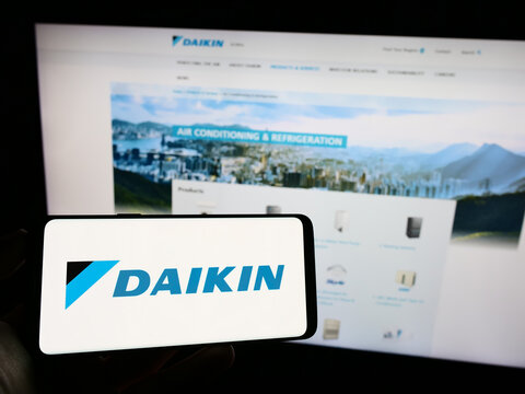 Stuttgart, Germany - 09-17-2023: Person holding cellphone with logo of Japanese company Daikin Industries Ltd. on screen in front of business webpage. Focus on phone display.