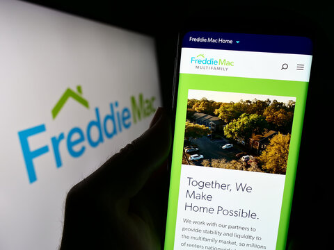 Stuttgart, Germany - 09-17-2023: Person holding cellphone with webpage of US mortgage company Freddie Mac on screen in front of business logo. Focus on center of phone display.