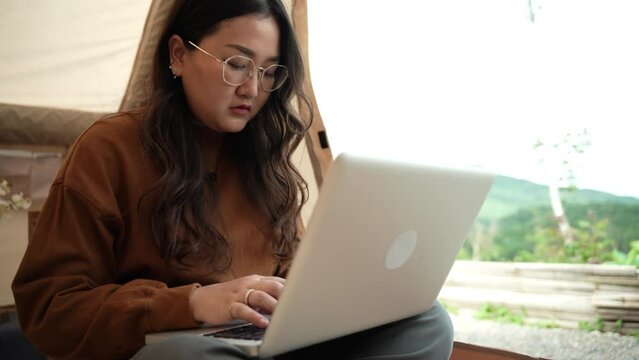 Asian woman digital nomad freelancer work typing on laptop&nbsp;while travelling camping.