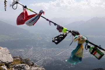 Handkerchiefs, bracelets and various objects left by tourists on the rope at the top of Innsbruck. Innsbruck seen from above.