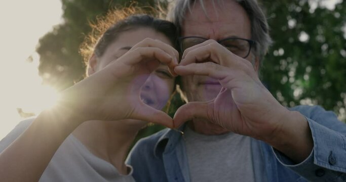 Father and daughter making a heart shape with their hands