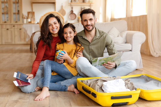 Cheerful Parents And Daughter Holding Sitting Near Travel Suitcase Indoor