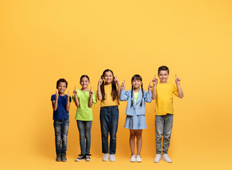Adorable diverse school aged kids pointing at blank space