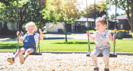 Naklejka premium Happy 3 years old girl on a swing. Happy kid on playground