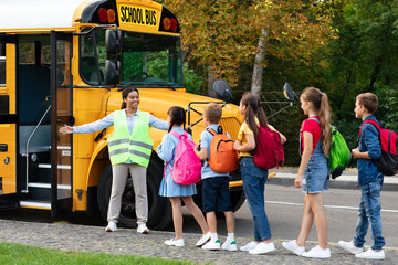 Black Female Teacher Assisting Children While They Entering School Bus