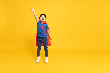 Superhero Asian boy with red cape and jumping isolated yellow background, Full body composition