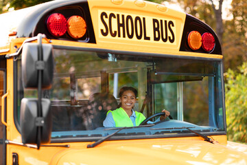 Portrait Of Happy Black Female Driver Driving Yellow School Bus