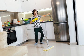 Male kid cleaning the floor and listening to the music. He is doing his chore and he is dancing