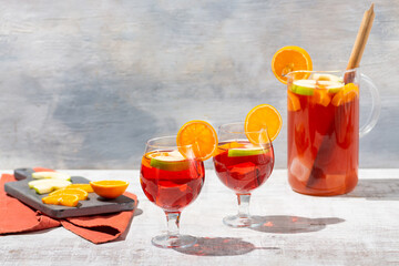 Sangria in a pitcher on white vintage table with apples and oranges and glasses