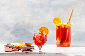 Sangria in a pitcher on white vintage table with apples and oranges and splash effect in glass