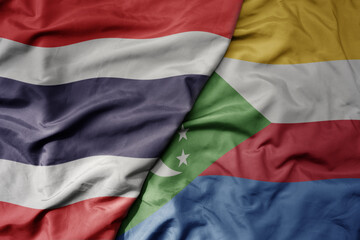 big waving national colorful flag of thailand and national flag of comoros .