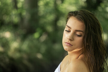 Beautiful brunette girl  bare shoulders is posing with wet hair outside.  Horizontally. 