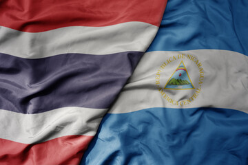 big waving national colorful flag of thailand and national flag of nicaragua .