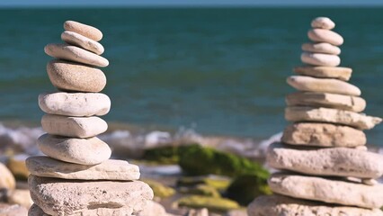A pyramid of stacked stones by the sea symbolizes balance and harmony in nature, creating a majestic contrast with the blue waves.
