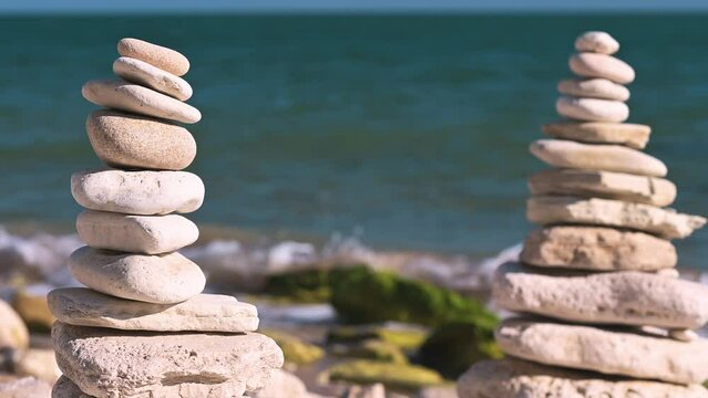 A pyramid of stacked stones by the sea symbolizes balance and harmony in nature, creating a majestic contrast with the blue waves.