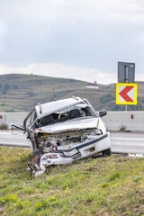 White car wrecked on the side of the road, abandoned after a head-on collision accident