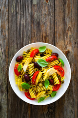 Antipasto pasta salad - fusilli pasta with various vegetables on wooden background
