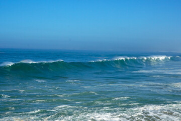 big waves rolling and breaking against cliff with high fountain of splashing water                              