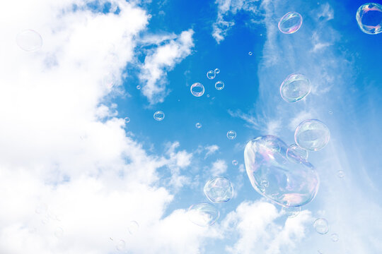 Soap multi-colored bubbles against a background of blue sky with clouds