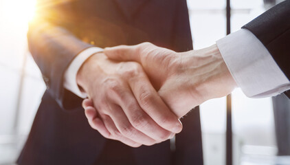 Close up of handshake on blurry conference room interior background. Partnership concept