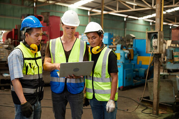 factory workers meeting and using laptop computer for work in machine factory